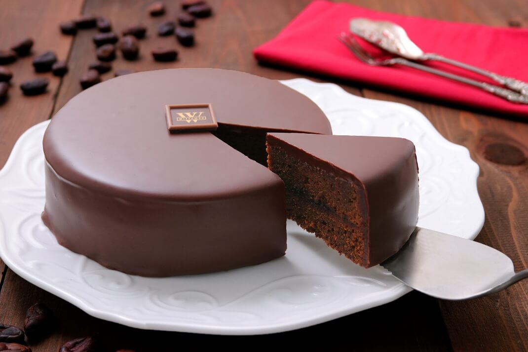 白いお皿の上にホール状のチョコレートケーキが置かれている様子