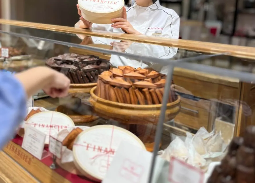  ショーケース前でお土産を選ぶ女性